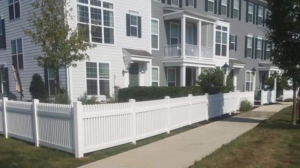 A newly installed white vinyl fence running along a sidewalk in front of townhouses by Low-Level Construction LLC in York, PA.