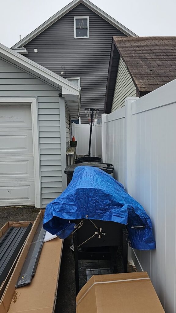 White vinyl fence materials ready for installation in a narrow space by Brothers Fence in Elizabeth, NJ.