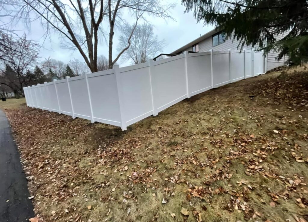 A white vinyl fence installed on sloped terrain by Fencing Company Of Omaha in Omaha, NE.