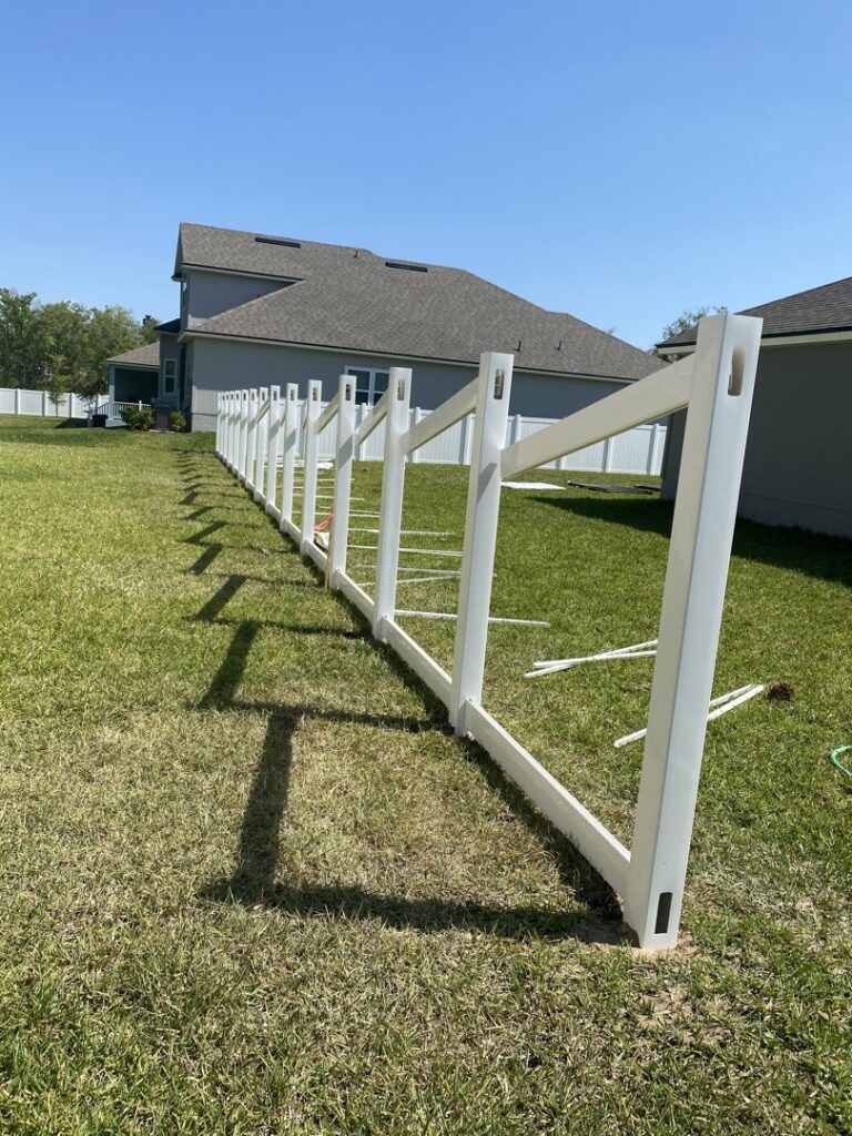 White vinyl fence panels being assembled and installed in a residential backyard by Top Fence LLC in Jacksonville, FL.