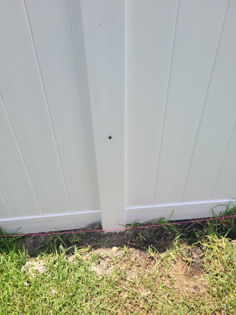 A white vinyl fence post with a pink string line for precise installation by R&R Fence Services in Jacksonville, FL.