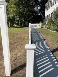 White vinyl fence posts and a picket fence installed along a pathway by OMA Fence,LLC in Weymouth, MA
