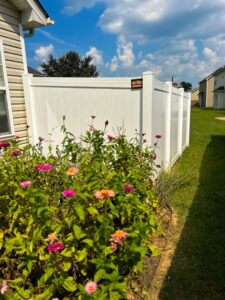 A white vinyl privacy fence installed next to a residential house with a garden in the foreground by Pro Fence in Decatur, AL