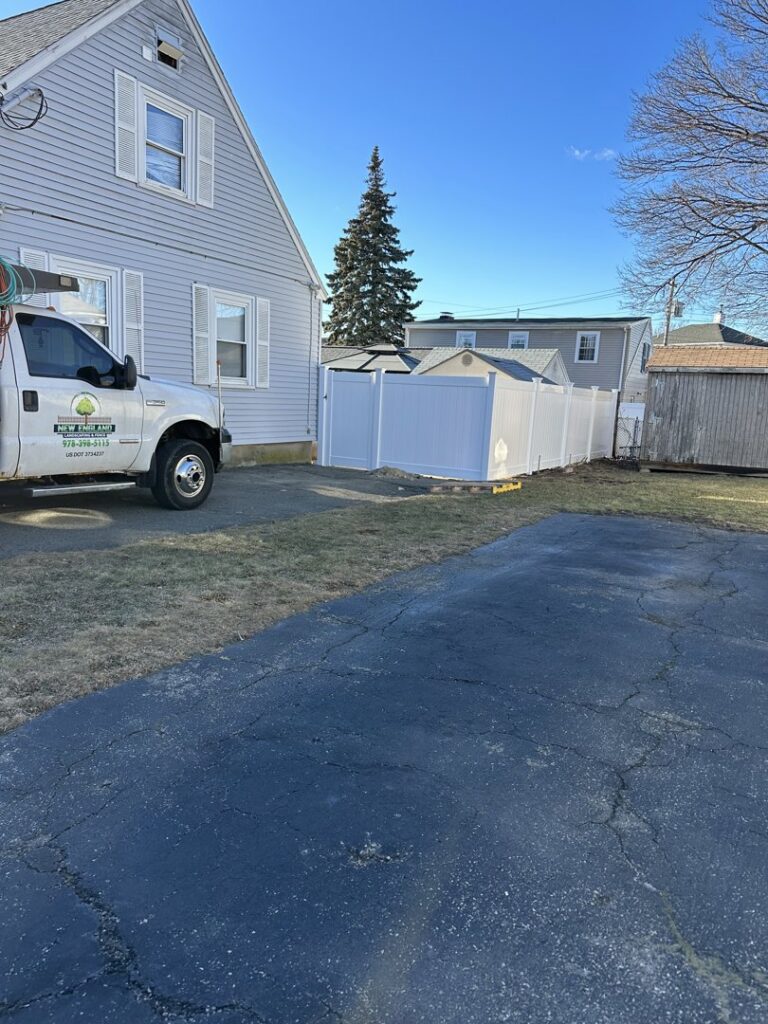 Newly installed white vinyl privacy fence at a residential property, showcasing work by New England landscaping and fence inc in Lynn, MA.