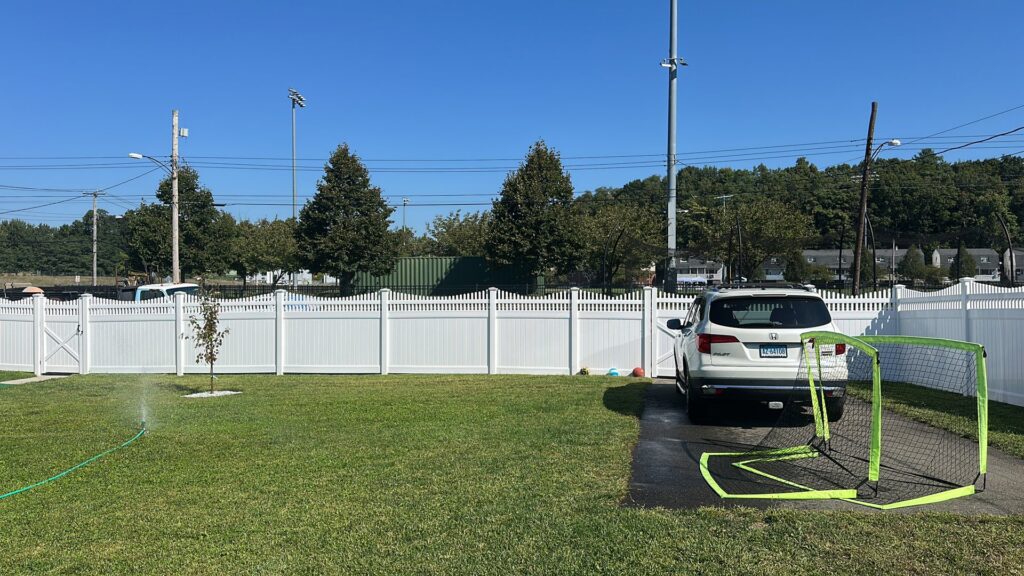 A white vinyl fence with a matching gate installed by White Eagle Fence Inc in New Haven, CT.