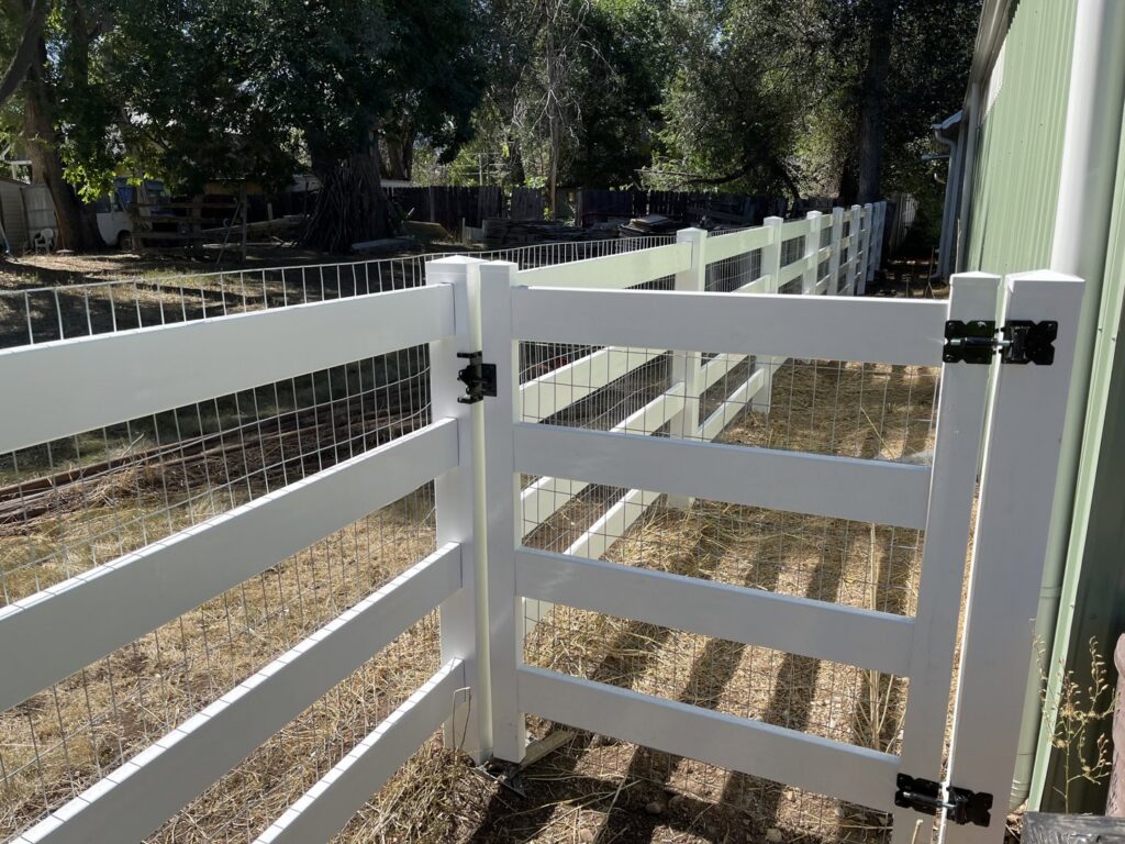 A white vinyl fence with wire mesh infill and a gate, providing a secure enclosure by North CO Fence & Deck in Greeley, CO.