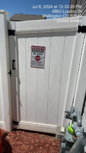 A white vinyl gate with a 'Beware of Dog' sign, installed by Border Fence, Inc. in Greeley, CO.