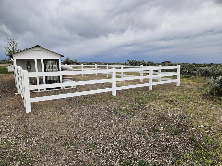 A white vinyl paddock-style fence enclosing an area next to a small shed, installed by Regan Fencing & Services in Nampa, ID.