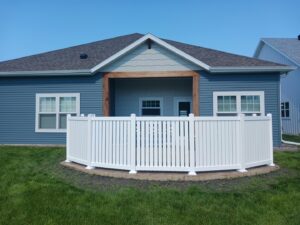 A white vinyl fence enclosing a patio area next to a house, installed by Aces Deck and Fence in Fargo, ND