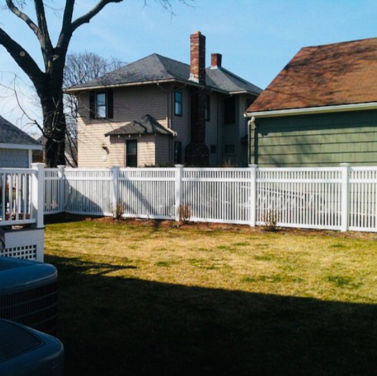 A white vinyl picket fence installed in a residential backyard by OMA Fence,LLC in Weymouth, MA