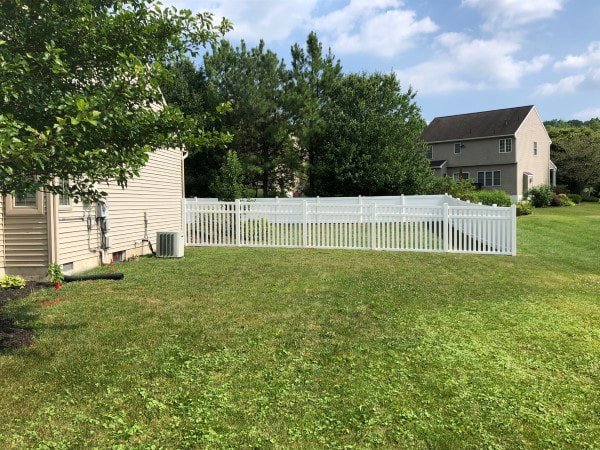 A white vinyl picket fence installed in a spacious backyard by Hitz Fence in Lebanon, PA.