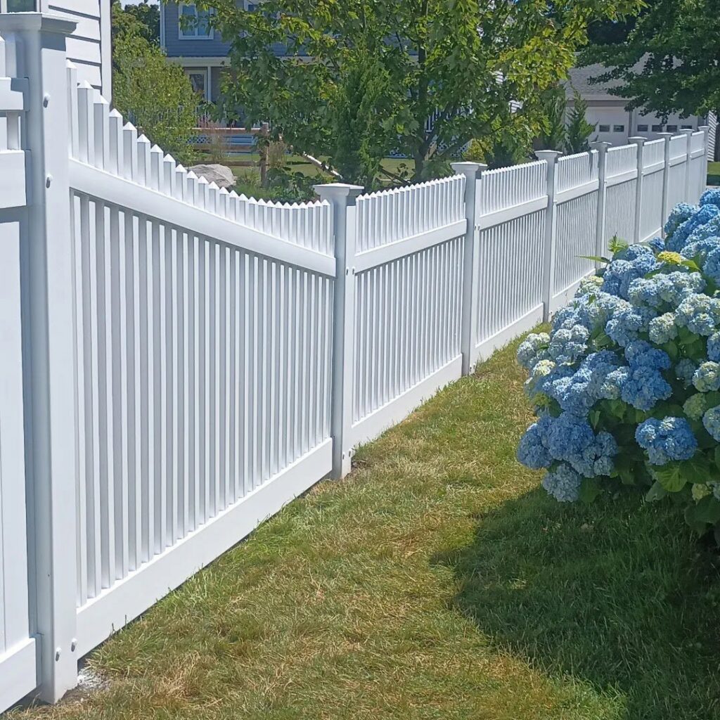A classic white vinyl picket fence with pointed tops, installed by Reilly Fence Inc in Cranston, RI.