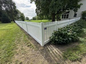 A white vinyl picket fence installed in a residential yard by Bostwick Fencing, LLC in Sioux City, IA.
