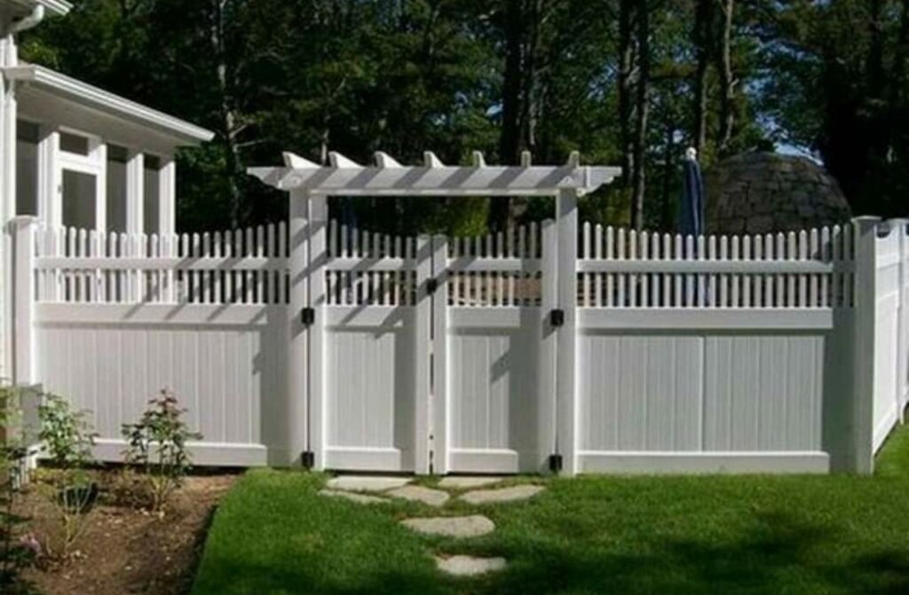 A beautiful white vinyl picket fence with a decorative gate and pergola archway by Valkyrie construction, LLC in Granville, OH.