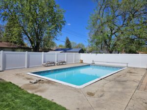 A white vinyl fence installed around a swimming pool by Aces Deck and Fence in Fargo, ND