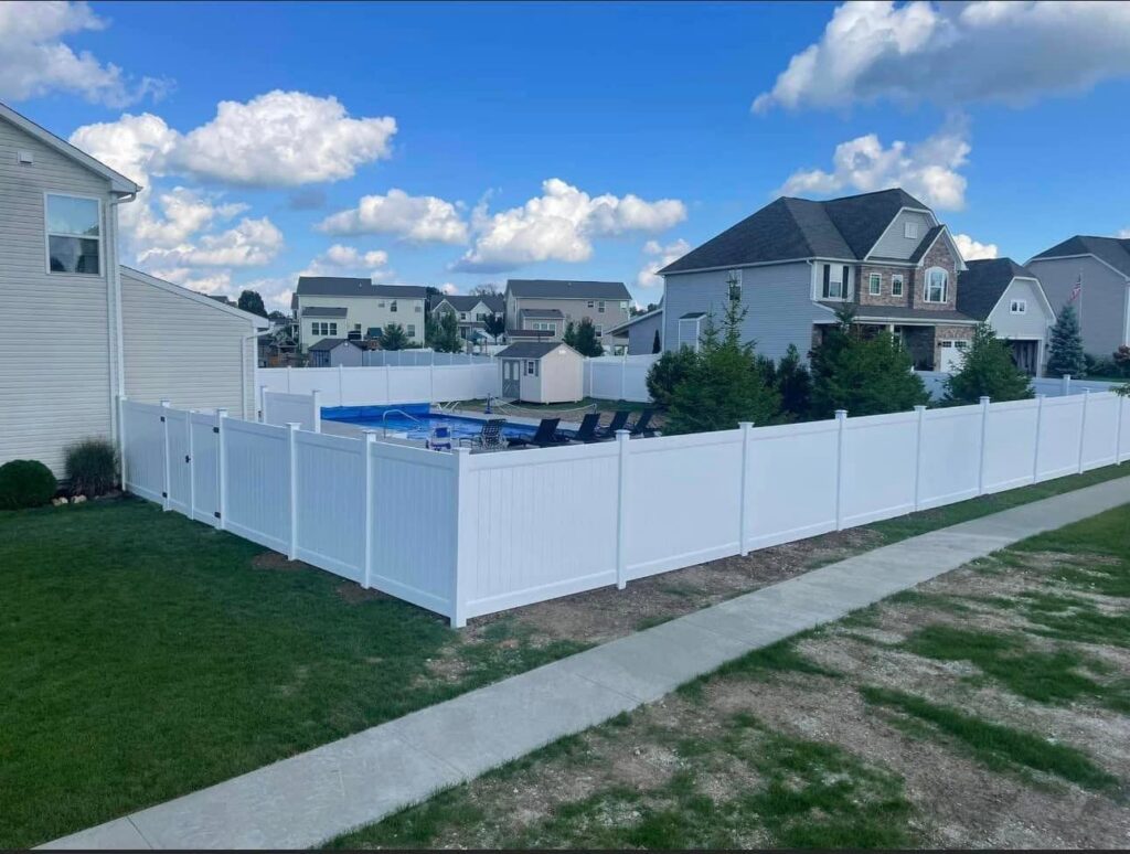 A white vinyl privacy fence enclosing a backyard with a swimming pool by Affordable Fencing in Parma, OH.