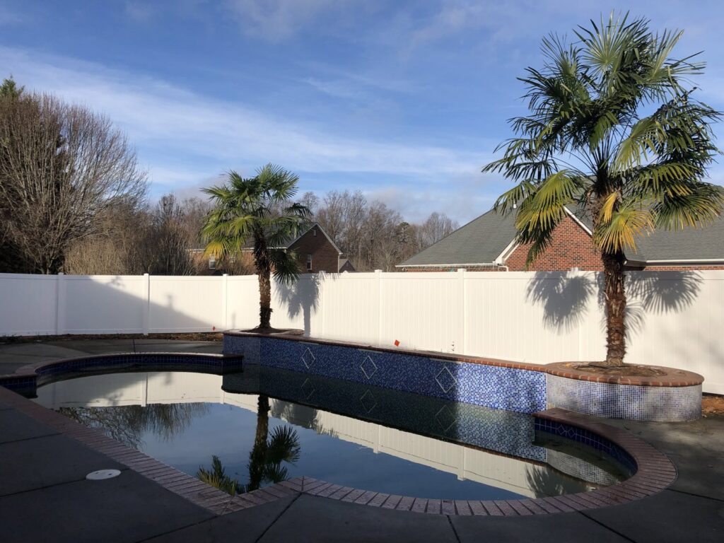 A white vinyl privacy fence installed around a swimming pool area by Fenceitforu LLC in Matthews, NC.