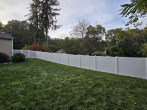 A backyard featuring both white vinyl privacy and picket fence installations by Homestead Fence in Cumberland, RI.