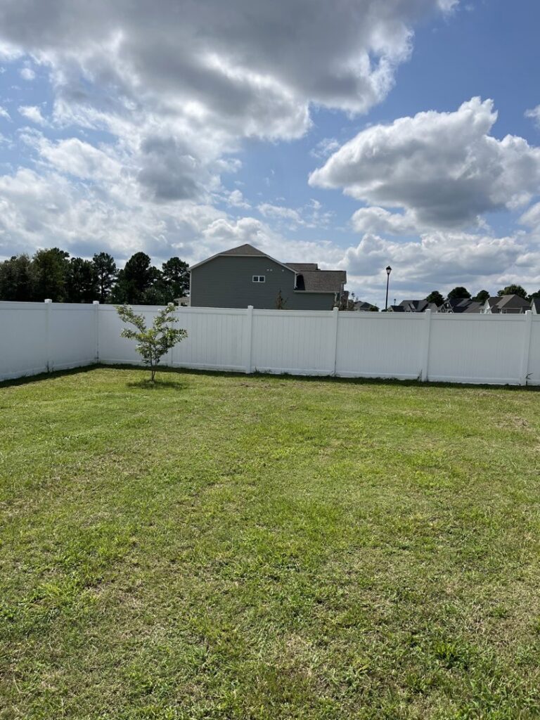 A pristine white vinyl privacy fence installed in a residential backyard by Aguilarfence services LLC in Clayton, NC.