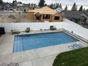 A white vinyl privacy fence enclosing a backyard swimming pool by Crows Quality Fencing in Spokane Valley, WA.