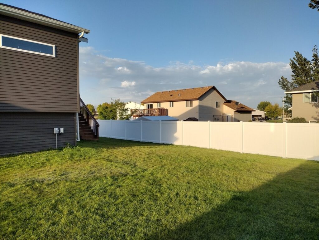 A white vinyl privacy fence installed in a backyard by Aces Deck and Fence, LLC in Fargo, ND.