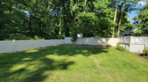 A newly installed white vinyl privacy fence with a gate in a residential backyard by Concord Fence Llc in Wilmington, DE