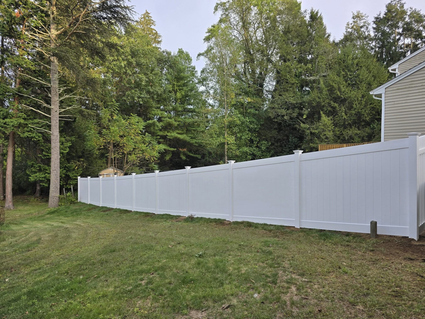 A long white vinyl privacy fence installed in a residential backyard by Homestead Fence in Cumberland, RI.