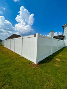 A white vinyl privacy fence installed around a residential backyard, with a Pro Fence sign, by Pro Fence in Decatur, AL