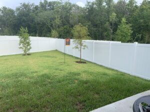 A newly installed white vinyl privacy fence enclosing a residential backyard by R&R Fence Services in Jacksonville, FL.