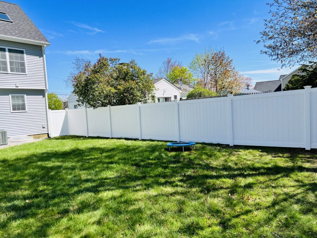 A long white vinyl privacy fence installed in a residential backyard by Ultra Fence LLC in Brookline, NH.