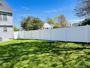 A long white vinyl privacy fence installed in a residential backyard by Ultra Fence LLC in Brookline, NH.