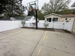 A white vinyl privacy fence enclosing a residential basketball court by Bostwick Fencing, LLC in Sioux City, IA.