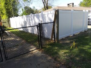 A white vinyl privacy fence transitioning to an existing chain-link fence with a wooden post by Pride Fence LLC in Overland Park, KS.
