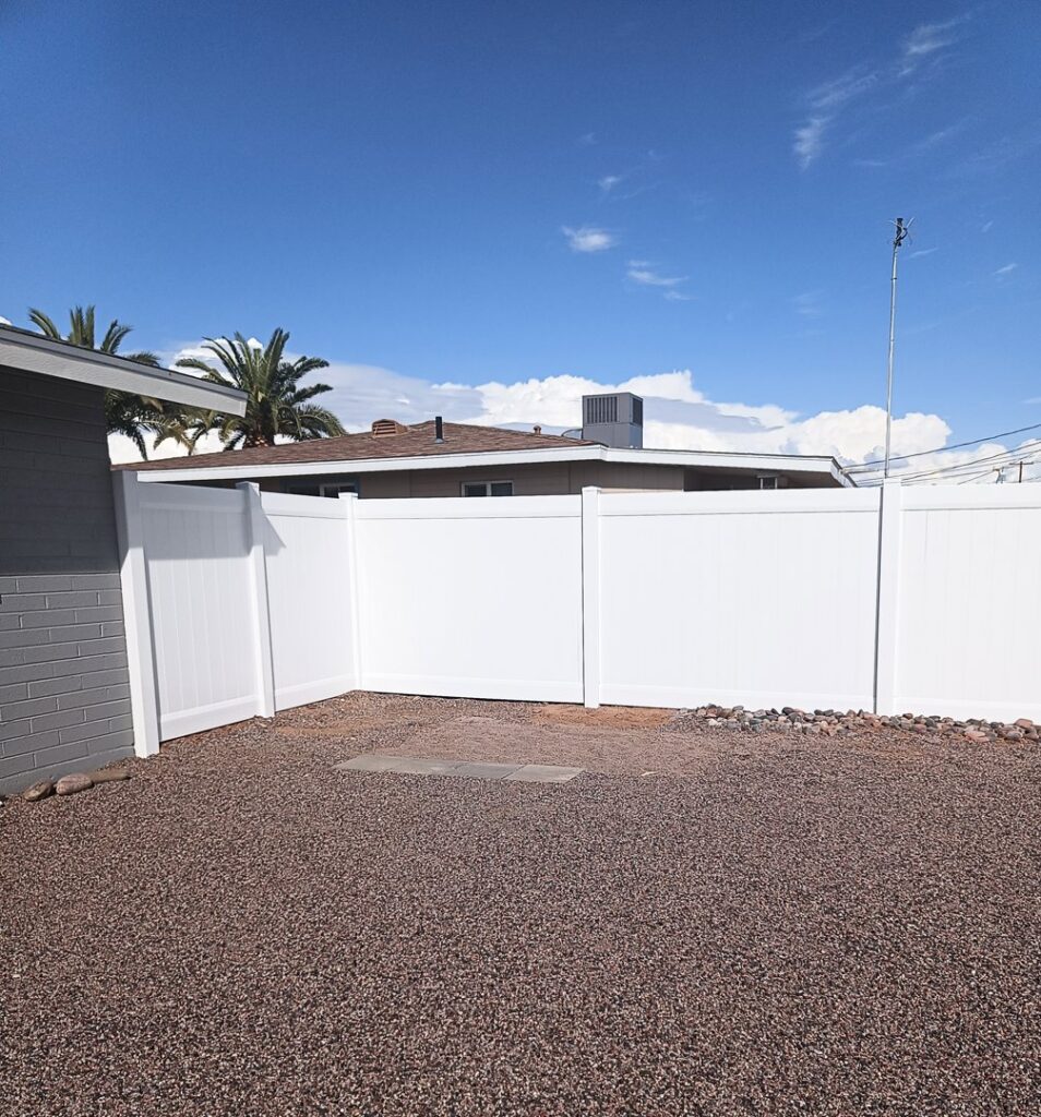 A white vinyl privacy fence installed in a corner of a residential yard by Competitive Fence Contractors LLC in Scottsdale, AZ.