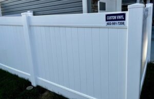 A white vinyl privacy fence with a business sign installed by Custom Vinyl Fabrication in Omaha, NE.