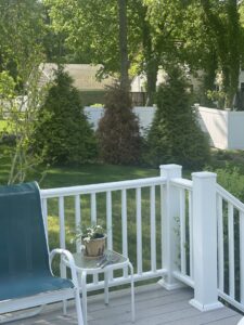 A white vinyl privacy fence in the background with a matching deck railing by OMA Fence,LLC in Weymouth, MA