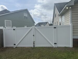 A white vinyl privacy fence with a double gate installed in a residential backyard by Fayetteville Fence Pros in Fayetteville, NC.
