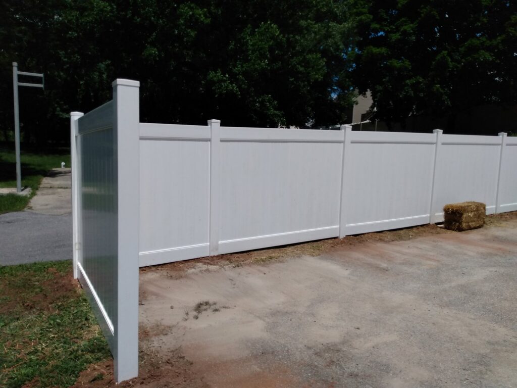 A white vinyl privacy fence installed along a driveway by Snyders Custom Fencing in York, PA.