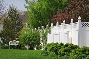 A pristine white vinyl privacy fence bordering a lush garden, expertly installed by Delmarva Facility Maintenance Services in Laurel, DE.
