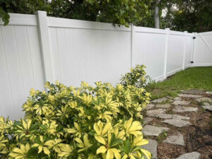 A pristine white vinyl privacy fence bordering a garden area, installed by Native Outdoors, LLC in Orlando, FL.