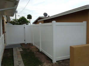 A white vinyl privacy fence with a matching gate installed next to a house by Hernandez Fence in Orlando, FL.