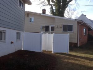 A white vinyl privacy fence with a gate enclosing a small outdoor area by Master Fences in Gaithersburg, MD.