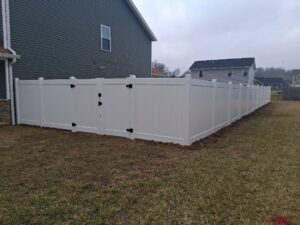 A long white vinyl privacy fence with a gate installed in a residential backyard by Morton Fence Solutions LLC in Indianapolis, IN.