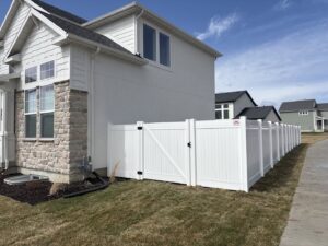 A white vinyl privacy fence with a gate installed in a side yard by Sublime Fencing LLC in North Logan, UT.