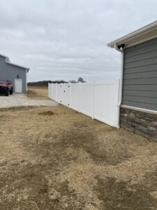 A clean white vinyl privacy fence installed alongside a house and barn by Petty Fence Company LLC in Evansville, IN.