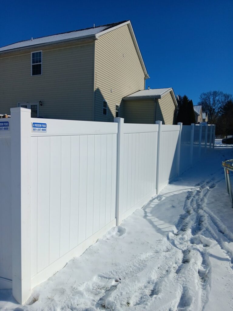 A pristine white vinyl privacy fence standing in a snowy backyard, installed by A Freedom Fence in Martinsburg, WV.