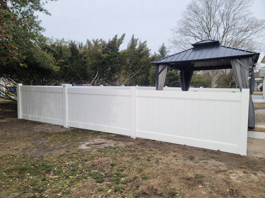 A newly installed white vinyl privacy fence in a residential backyard by AllMasterfence in Toms River, NJ.