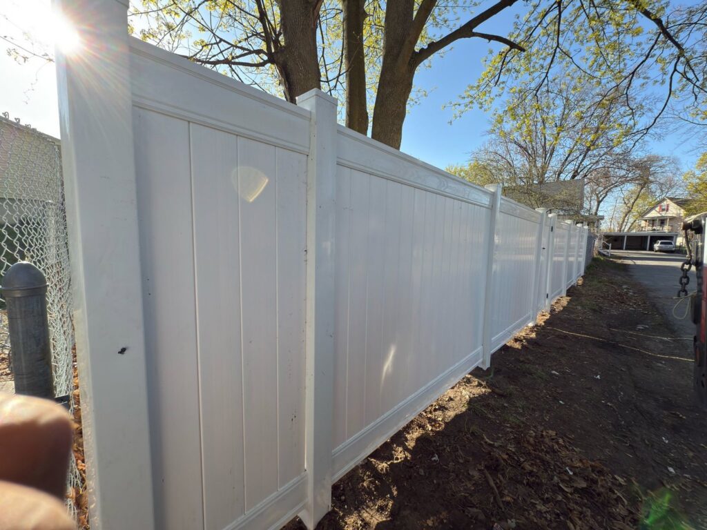 A section of newly installed white vinyl privacy fence by Matul Fence Inc in Lynn, MA