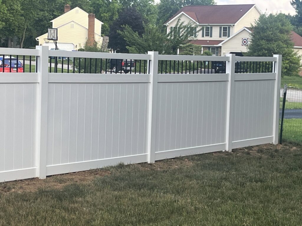 A newly installed white vinyl privacy fence with decorative black top rails in a residential backyard by Future Solutions Fence Supply in York, PA