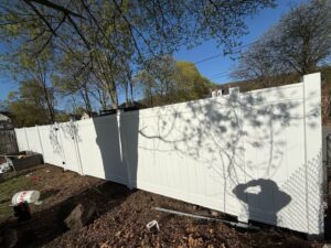 Installation of a white vinyl privacy fence in a residential area by Matul Fence Inc in Lynn, MA